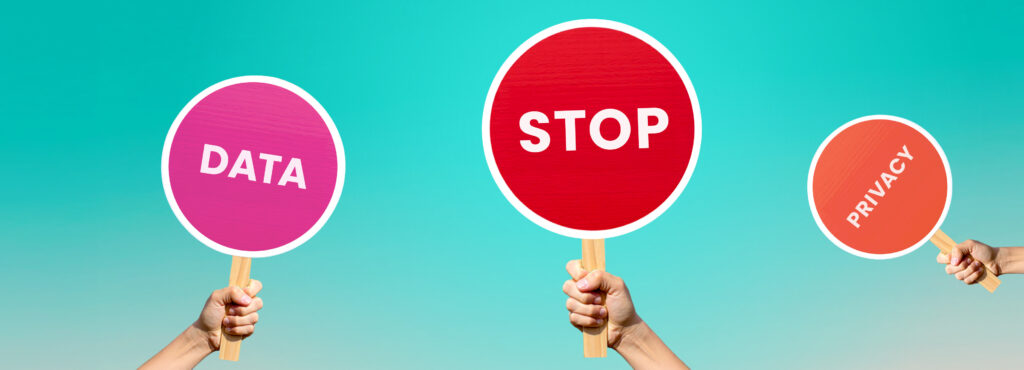 Drei Hände halten Schilder mit den Worten 'DATA', 'STOP' und 'PRIVACY' vor einem blauen Hintergrund.